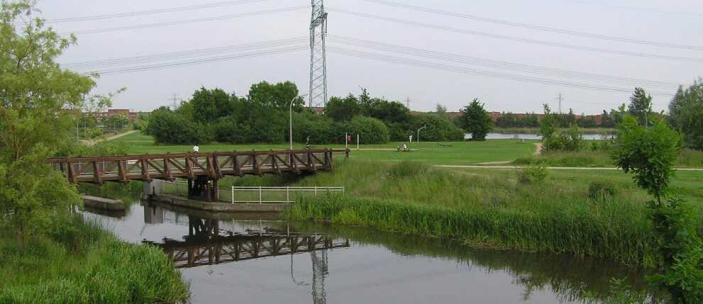Open green space with a bridge crossing a river