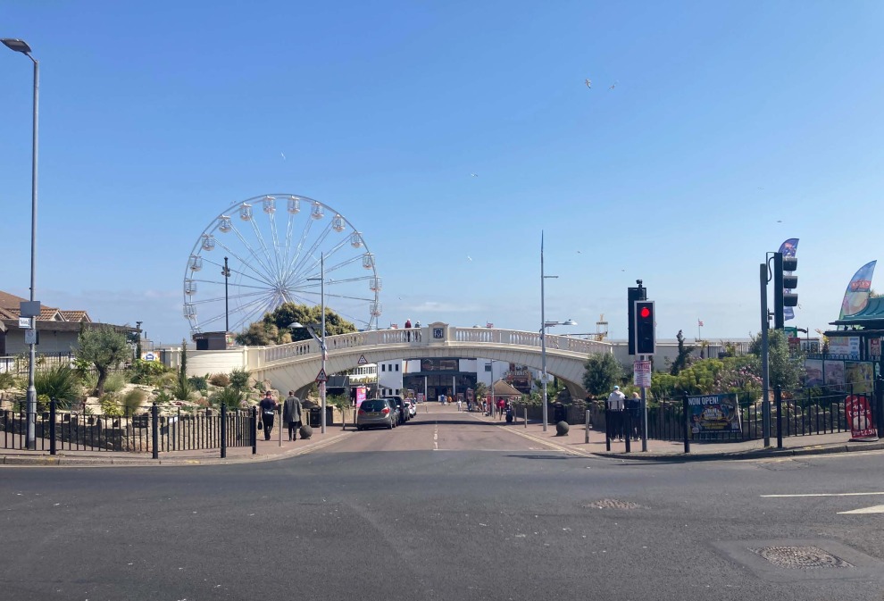 Clacton-on-Sea with a Ferris wheel and bridge in the background and a road in the foreground.