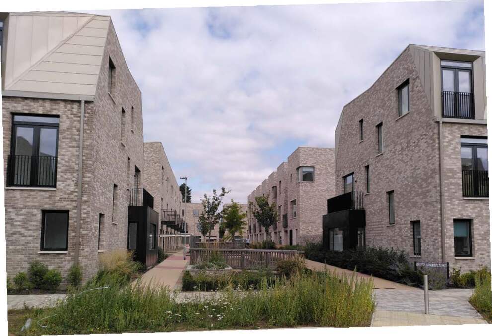 Modern housing complex with a path separating them and shrubbery